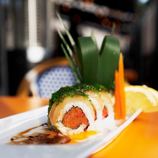Sakana Sushi Lounge's sushi roll with red filling, topped with green seaweed and orange slices.
