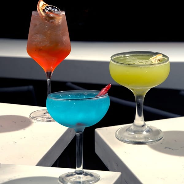 Three colorful cocktails: red, blue, and green, on white blocks at Sakana Sushi Lounge DTLA.